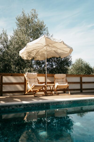 Two sun chairs with umbrella by a serene pool in Ortaca, Türkiye.