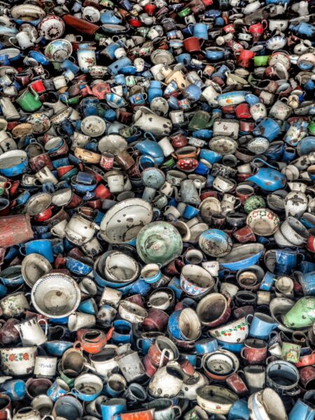 A poignant image of abandoned enamel cups and pots, symbolizing history at Auschwitz.
