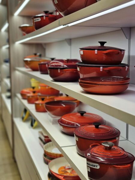 Vibrant array of pots and pans on store shelves in an indoor kitchenware section.