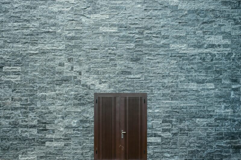A minimalist stone brick wall featuring a simple wooden door, showcasing architectural design.