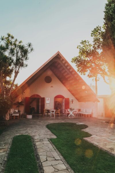 Beautiful A-frame house surrounded by lush garden in warm sunlight, creating a serene and inviting atmosphere.