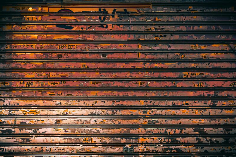 A close-up of a rusty metal shutter with colorful graffiti in Hong Kong.
