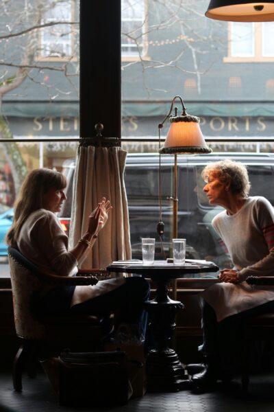 Intimate conversation between two women in a cozy New York City café, creating a warm atmosphere.
