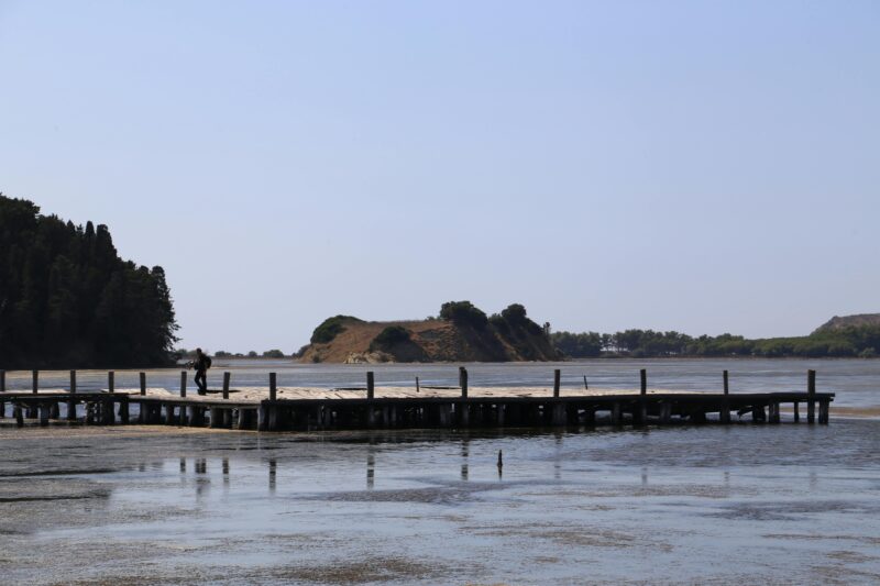 A tranquil pier scene with a lone person against a scenic lakeside view.