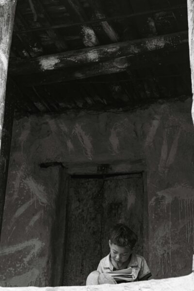 Reflective child reading in a rustic setting.