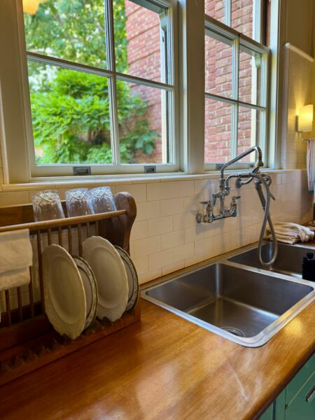 A traditional kitchen sink area with plates, faucet, and window view.
