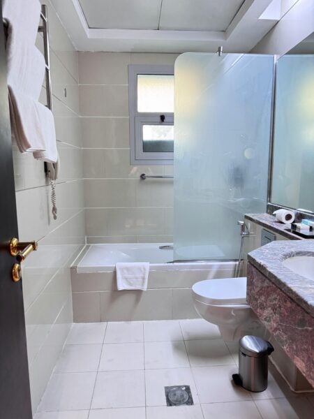 Bright modern hotel bathroom featuring a shower, towels, and toiletries.