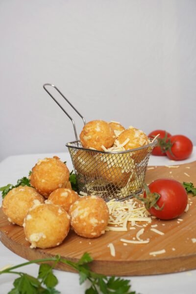 Crispy cheese balls with tomatoes on a wooden board, perfect snack idea.
