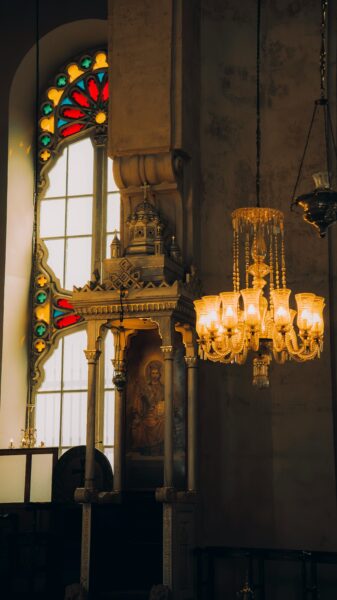 A beautiful church interior featuring a stained glass window and a vintage chandelier.