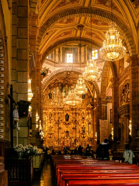 A richly decorated cathedral interior with chandeliers and ornate architecture.