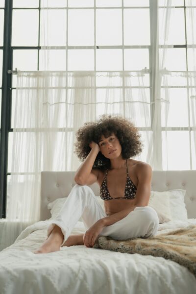 Relaxed afro-haired woman in cozy bedroom setting
