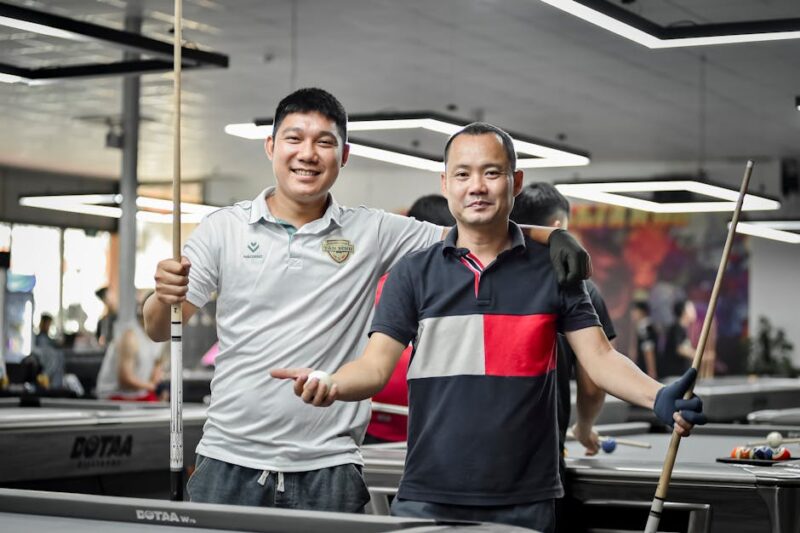 Two friends enjoying a game of pool indoors, capturing a moment of joy and camaraderie in Hanoi.