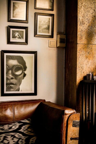 Vintage-styled interior with leather couch and framed artwork on a textured wall