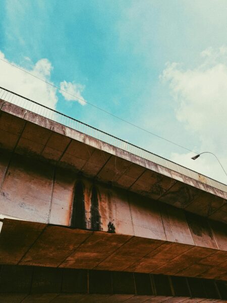 Low angle view of a weathered bridge against a clear blue sky.
