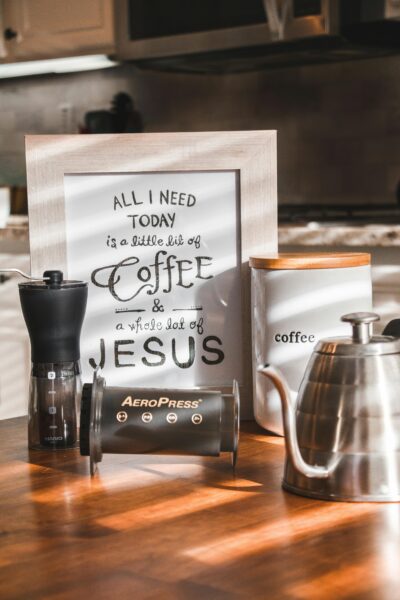 Cozy kitchen scene with AeroPress coffee maker, grinder, and framed motivational coffee quote.