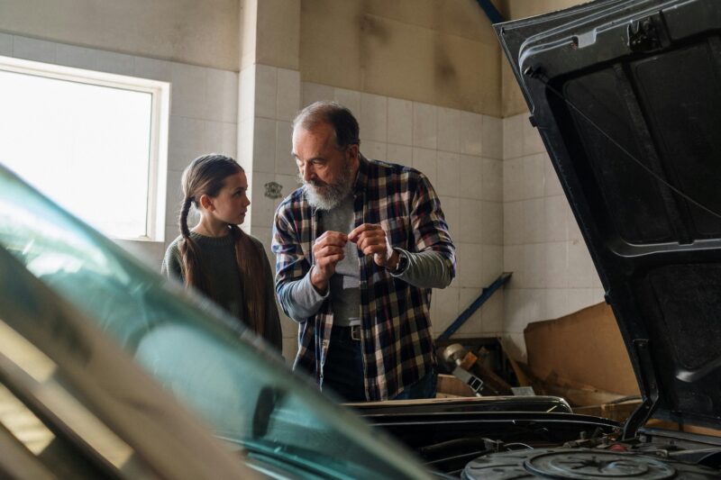 Father and daughter bonding over car repair in a garage workshop.