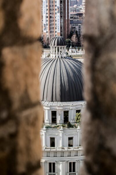 View of a dome through ancient walls in Skopje, highlighting architectural contrast.
