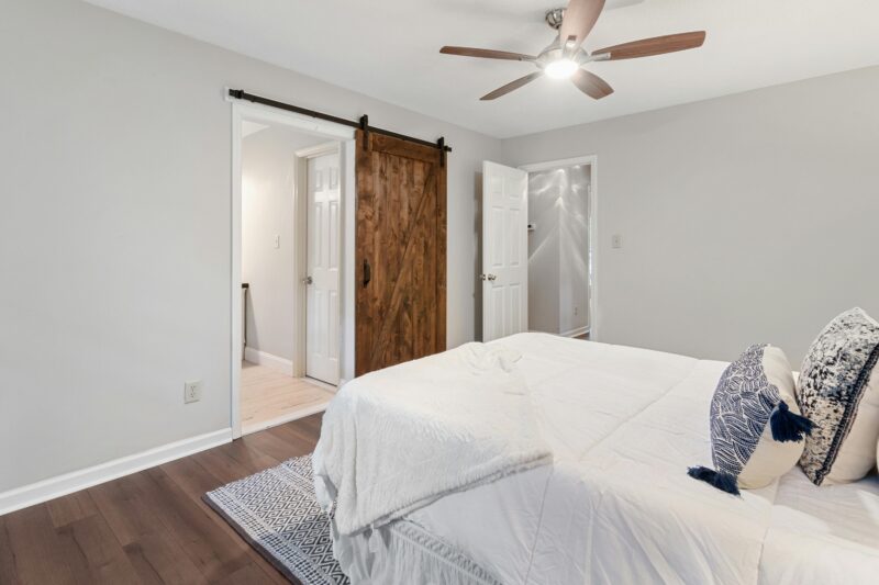 Cozy and stylish bedroom featuring a wooden sliding door and sleek ceiling fan, perfect for a contemporary home decor