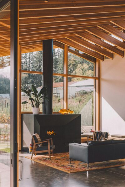Sunlit modern living room with fireplace and glass wall, offering comfort and style.