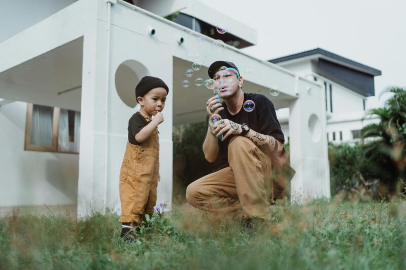 Father and son bond while playing with soap bubbles in the yard