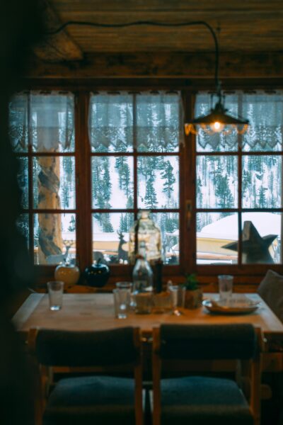 A serene rustic dining room with a snowy forest view, perfect for a peaceful retreat.