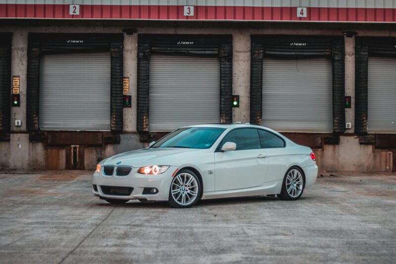 A sleek BMW parked in front of industrial loading docks, showcasing elegance.