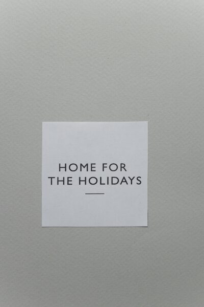 A simple 'Home for the Holidays' greeting card on a textured gray surface.