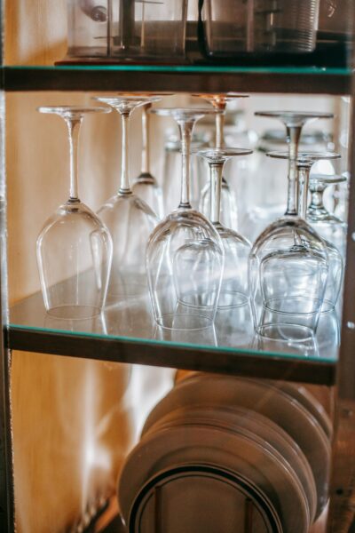 Glass and ceramic plates on wooden shelves under glass in kitchen at home.