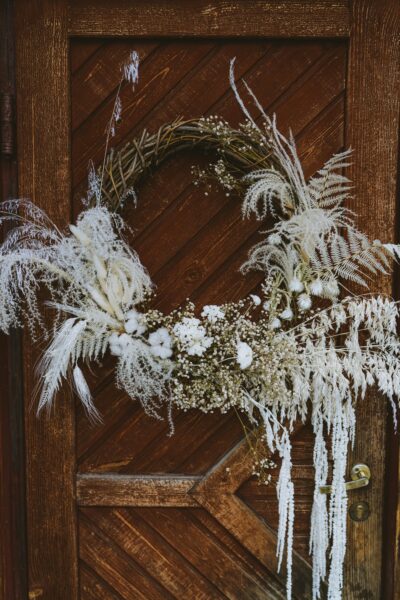 A beautiful rustic wreath hanging on a wooden door, featuring dried flowers and natural elements.