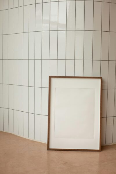 A minimalist interior featuring a blank vertical frame against tiled wall, offering ample copy space.