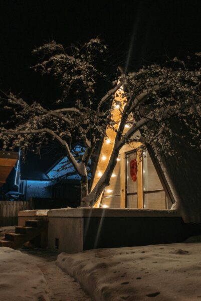 A snowy A-frame cabin illuminated with warm lights, capturing a tranquil winter night scene.