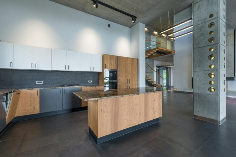 Interior of kitchen with multicolored cabinets and wooden table in lobby of light apartment