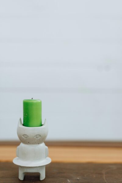 Elegant handmade cat figurine candle holder with a vibrant green candle on a wooden table.