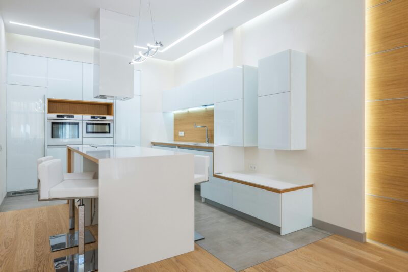 A spacious and contemporary minimalist kitchen interior with white and wooden elements.