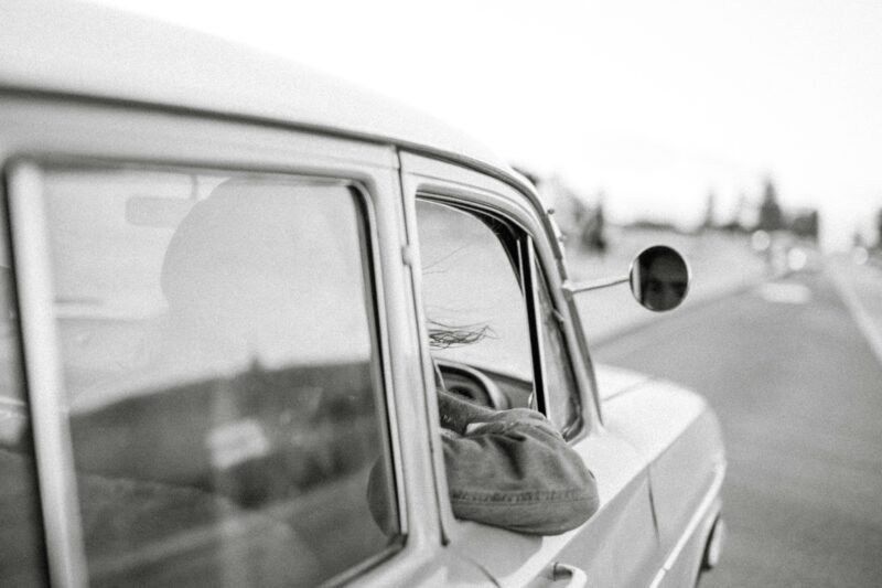 Vintage car journey with a person enjoying the view.