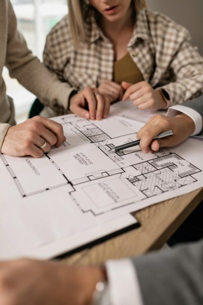 People discuss architectural plans in a real estate planning session, highlighting teamwork.