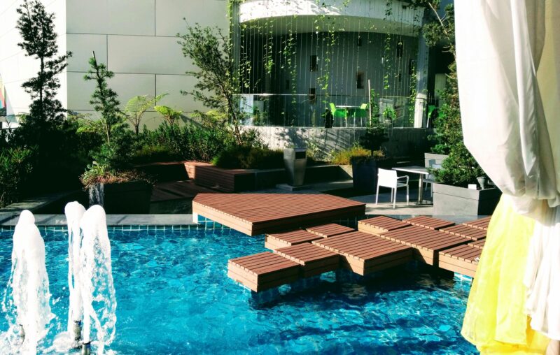 A luxurious outdoor pool area with stylish decking and a beautiful fountain, perfect for relaxation.