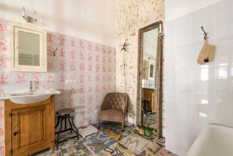 Stylish bathroom featuring vintage design with patterned tiles and a large mirror.