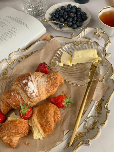 Elegant arrangement of croissants, strawberries, blueberries, and tea for a classic French breakfast.