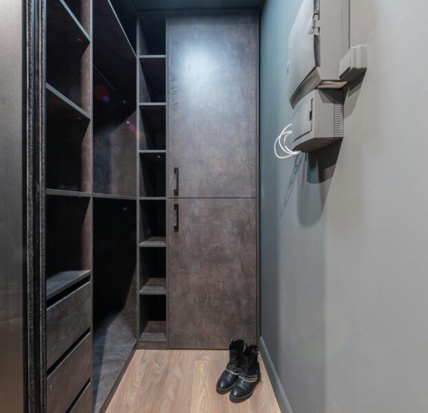 Spacious modern walk-in closet with shelves and leather boots on the floor