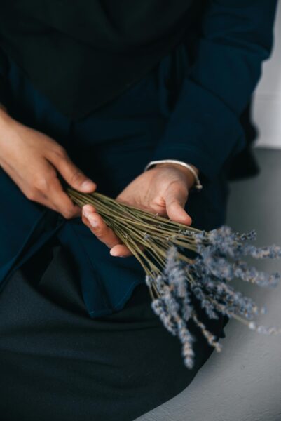 A close-up image of hands gently holding a bundle of lavender stems, evoking calmness and serenity.