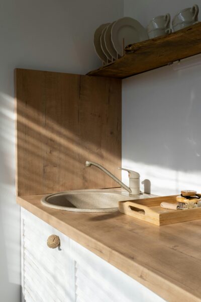 A modern minimalist kitchen showcasing a wooden sink area with natural sunlight.