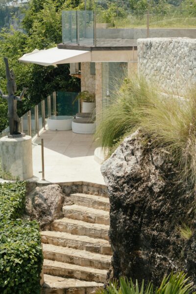 A luxurious terrace with stone steps, lush greenery, and a modern statue.