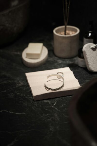 A sophisticated silver bracelet displayed on a stylish bathroom countertop with modern accessories.