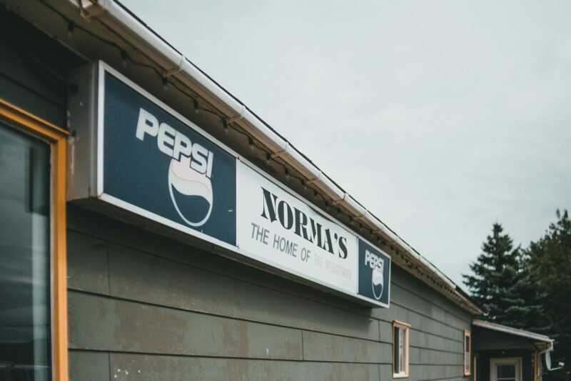 Photo of Norma's Restaurant exterior featuring a vintage Pepsi sign on a cloudy day.