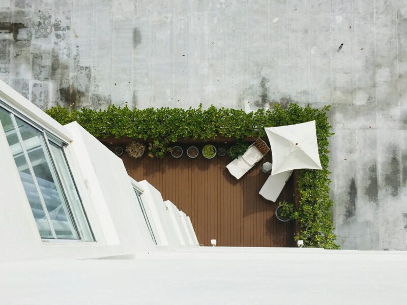 High-angle photography of chaise lounge and umbrella at daytime