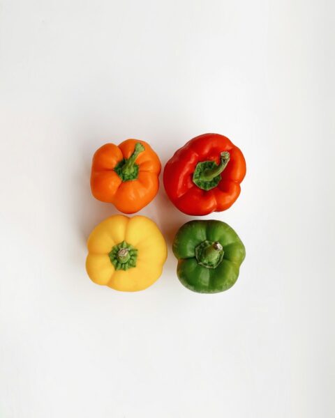 Four assorted-colored bell peppers in a container.