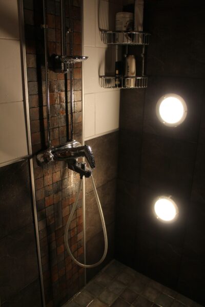 Gray stainless steel faucet in a wet shower.