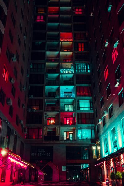 Buildings at night with a city skyline in the background.