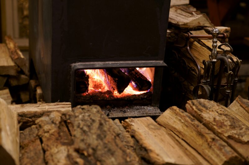 A black wood burner near brown firewood